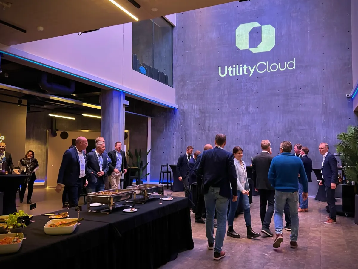 Guests mingling at a reception under a wall projection of the UtilityCloud logo